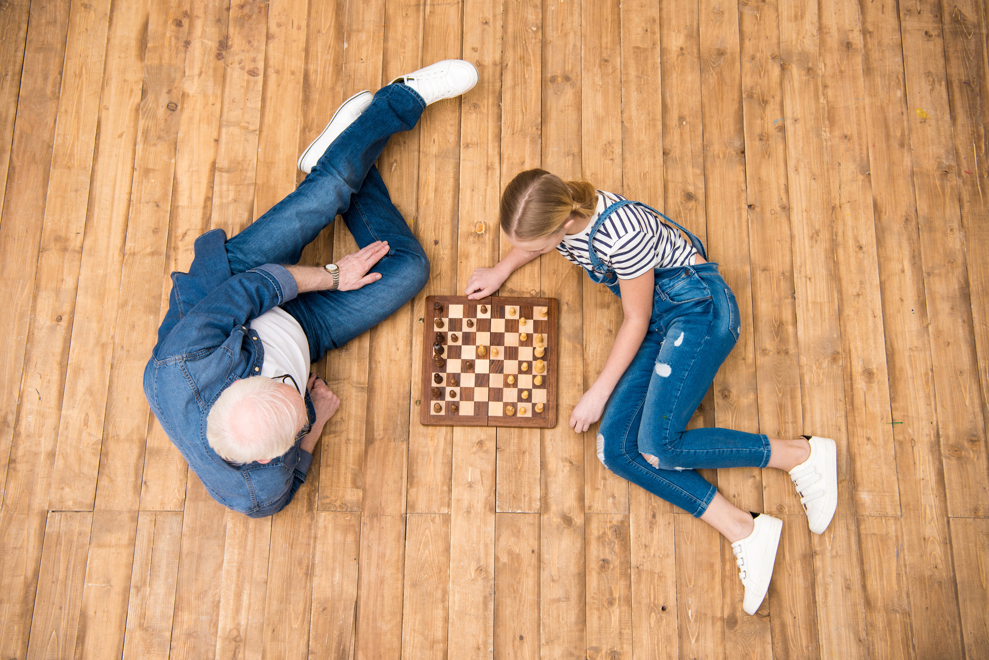 Girl and her father playing chess shown from above